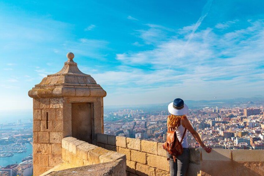 A person standing on a stone wall overlooking a cityscape. 3
