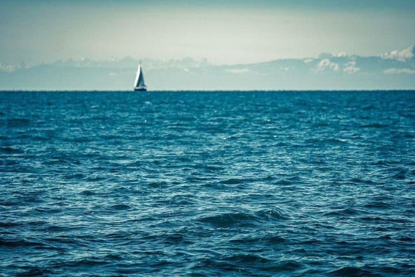 A sailboat on a calm sea with distant mountains. 2
