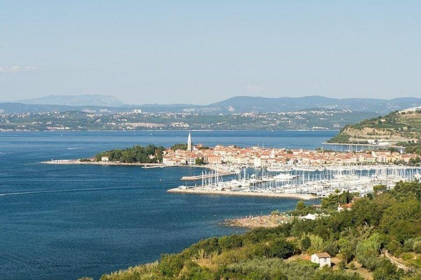 A coastal town with a marina, a prominent church, and a hilly landscape in the background. 3