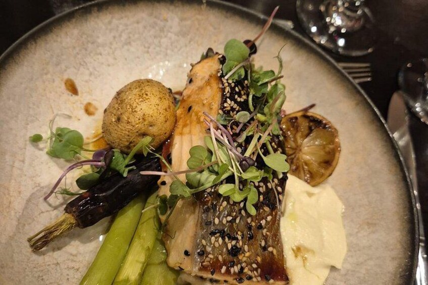 Un plato de comida con pescado, espárragos y una rodaja de limón. 1