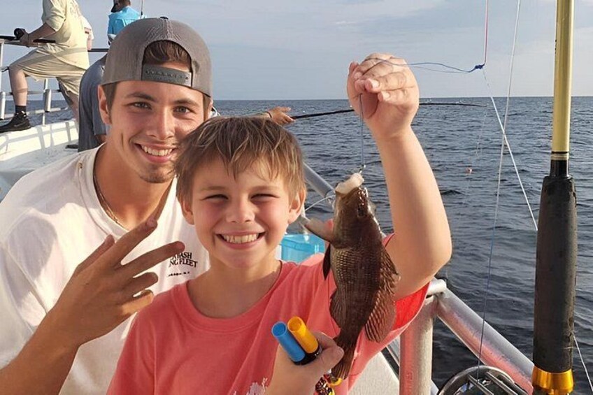 A person holding a fish, a boat, and a fishing rod. 5