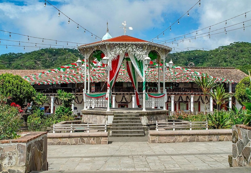 A gazebo with a red roof, surrounded by greenery and a stone pathway. 1