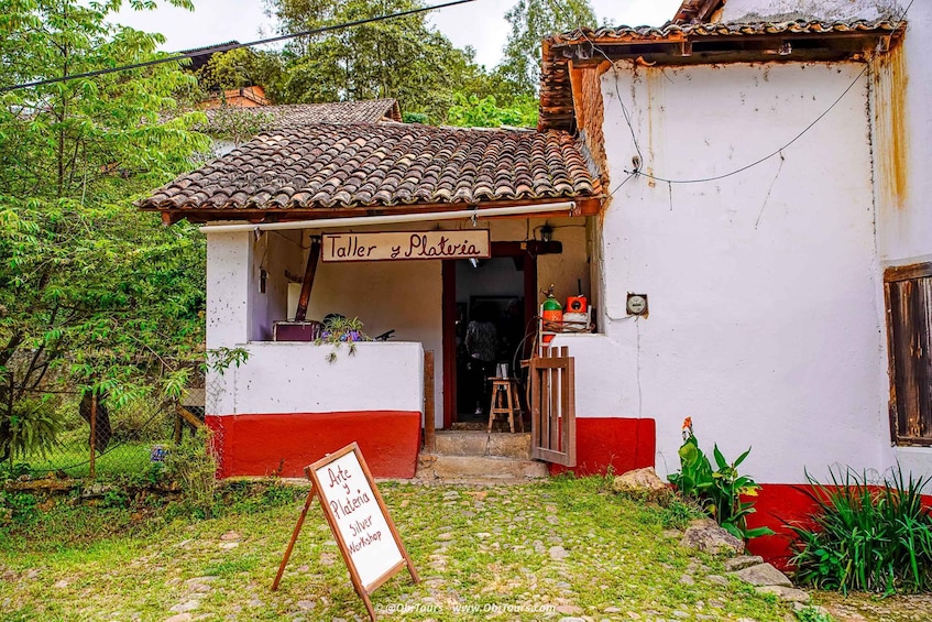 A small workshop named 'Taller y Plateria' with a tiled roof and a red and white facade. 3