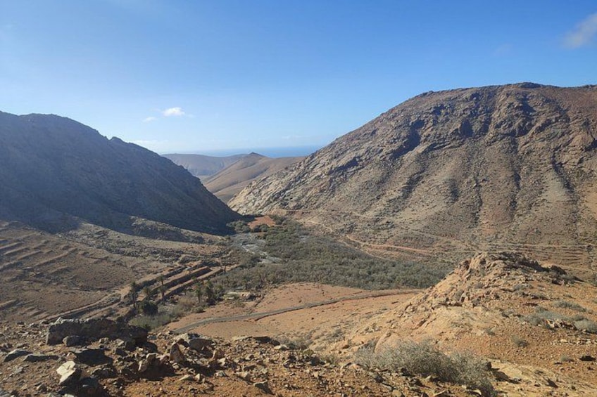 A mountainous landscape with a valley, rocky terrain, and sparse vegetation. 5