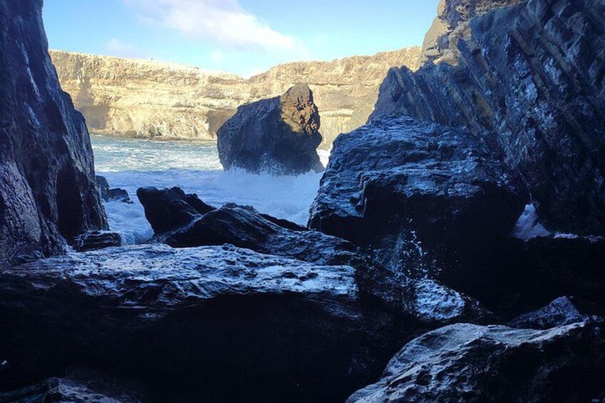 A rocky coastal landscape with waves crashing against large boulders. 3