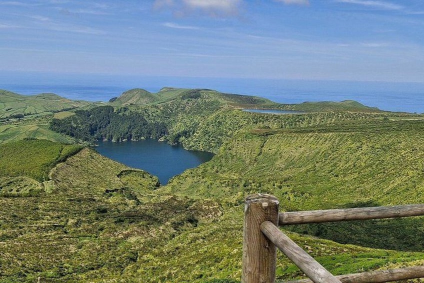 Un paisaje montañoso con un lago, una valla de madera y cielo despejado. 1