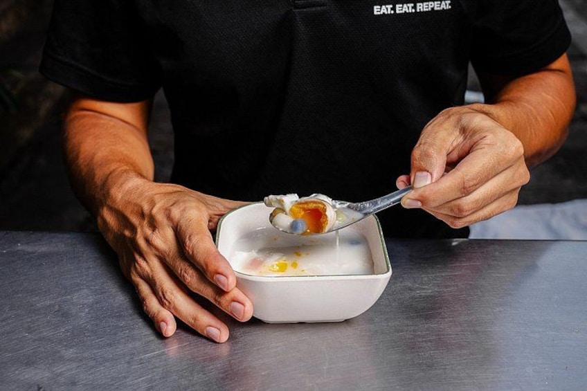 A person in a black shirt with the text 'EAT. EAT. REPEAT' scooping food from a white bowl. 2