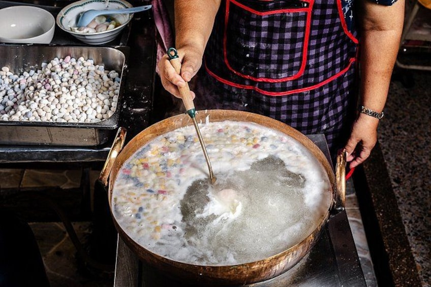 A person cooking in a large pot with a ladle. 3