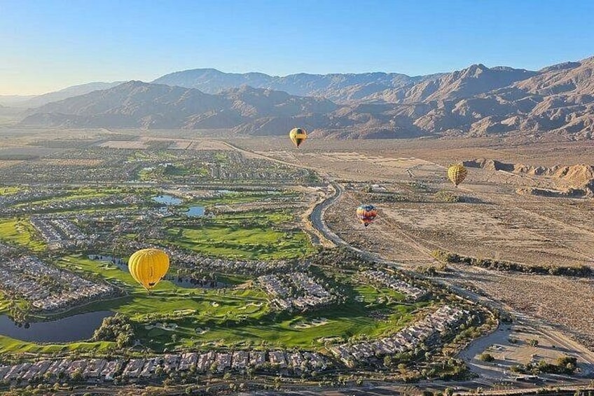 Een woestijnlandschap met luchtballonnen, een rivier en een stad. 3