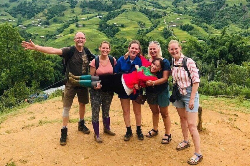 A group of people on a dirt path with a scenic view of green hills and a river in the background. 4