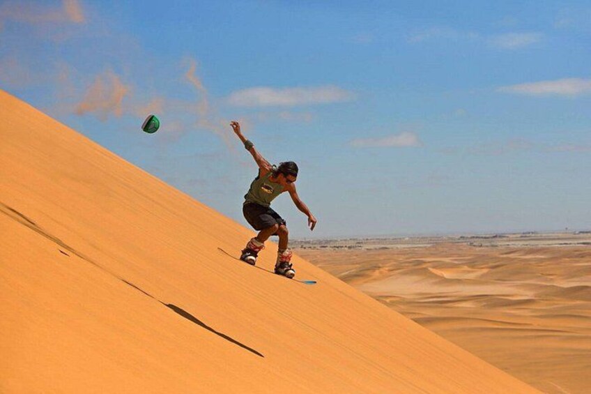 Una persona montando en patineta por una duna de arena. 1