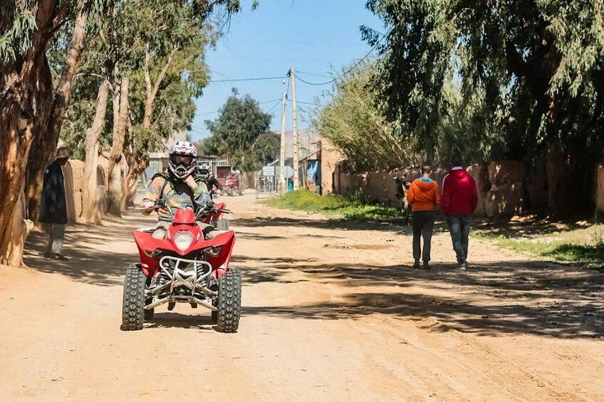 Un camino de tierra con un cuatriciclo rojo al frente y dos personas caminando al fondo. 5