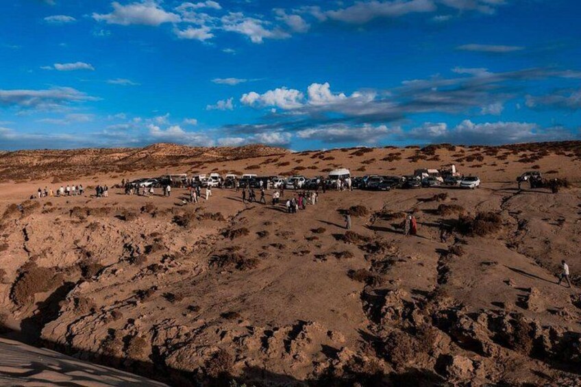 Paisaje desértico con un grupo de vehículos y personas. 3