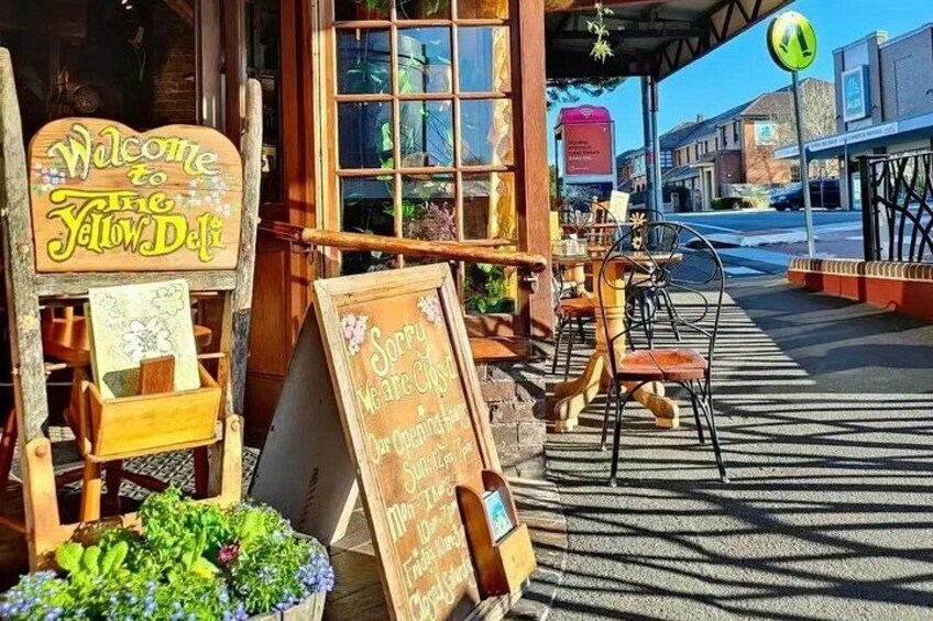 A restaurant named 'Yellow Deli' with outdoor seating and a chalkboard sign. 2
