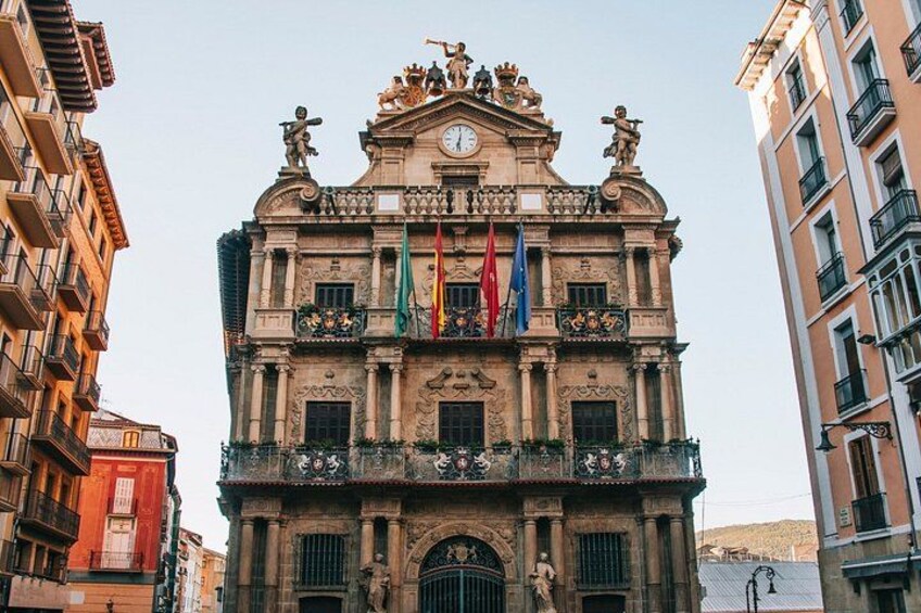 A historic building with ornate architecture, multiple flags, and statues. 4