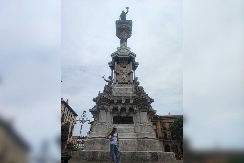 A tall monument with a statue on top, surrounded by buildings. 4