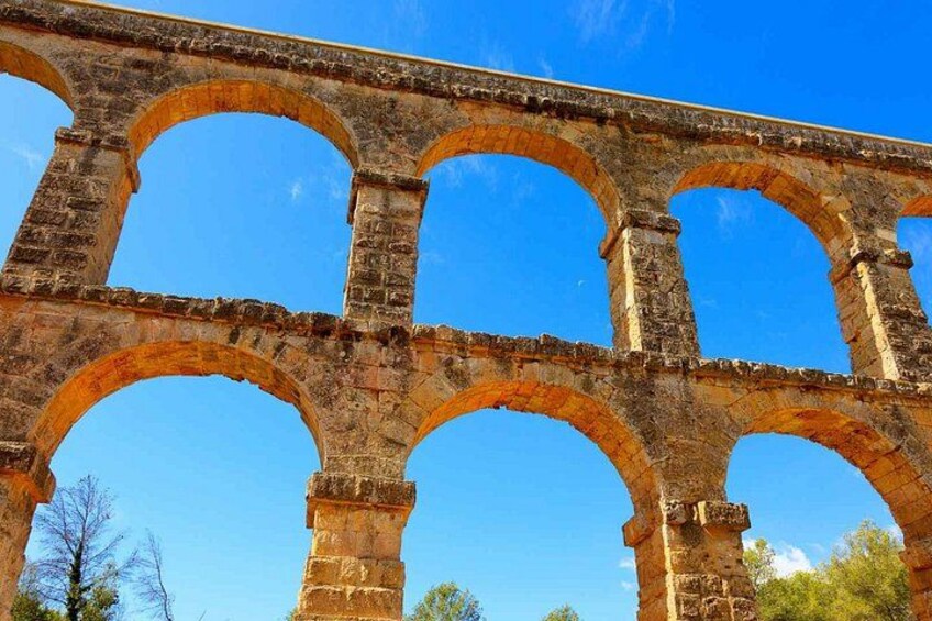 A stone aqueduct with multiple arches under a clear blue sky. 2