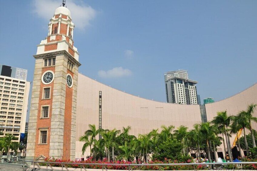 A modern building with a clock tower, palm trees, and a clear blue sky. 4