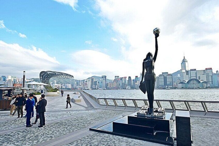 A statue of a person holding a soccer ball in a public square with a city skyline in the background. 3