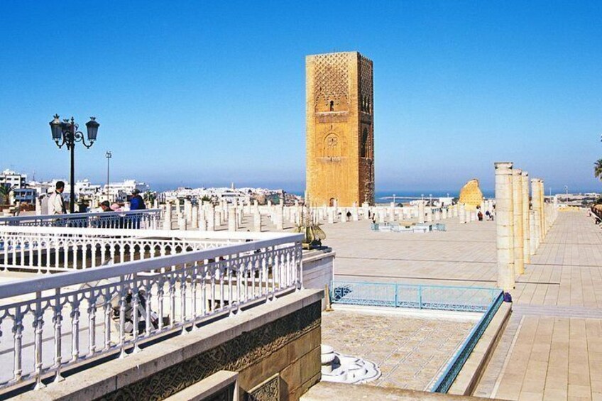 Un paseo marítimo con una torre destacada, barandas blancas y cielo despejado. 1