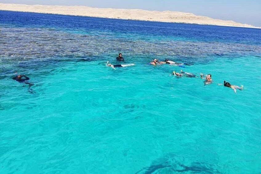 A group of people snorkeling in clear turquoise water with a sandy beach in the background. 3
