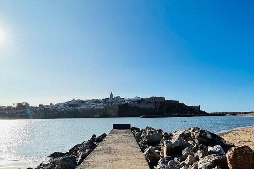 A coastal scene with a pier leading to a fortified building on a hill. 5