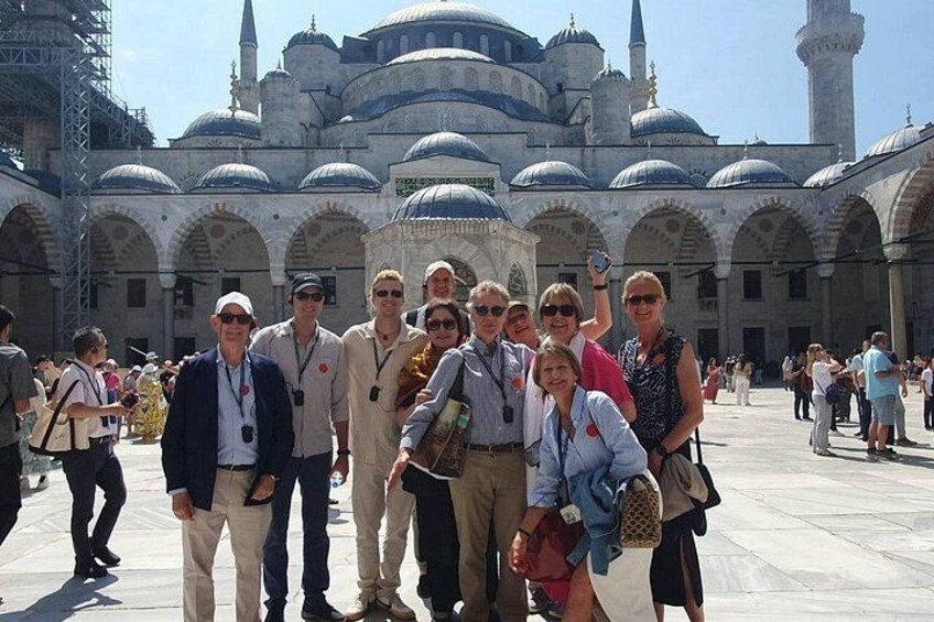 A group of people posing in front of a historic building with domed architecture. 3