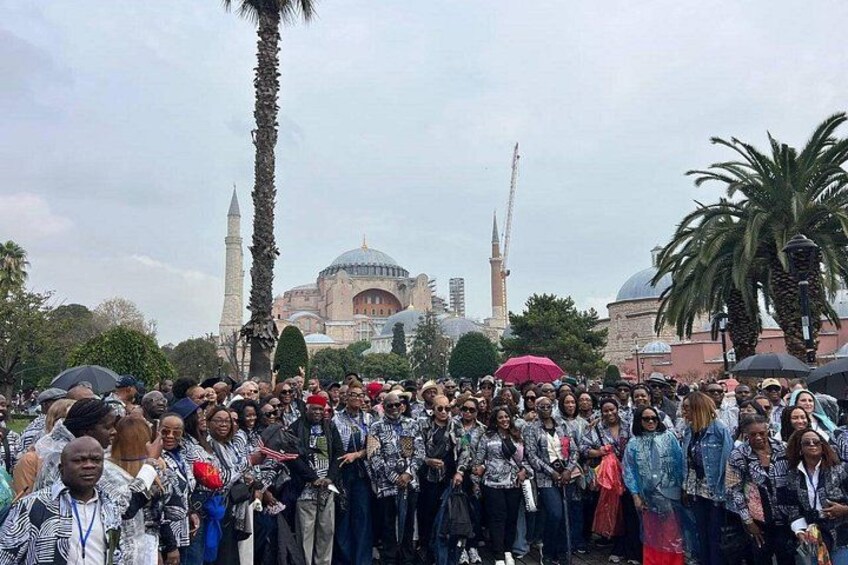 A large group of people gathered in front of a mosque with a minaret and dome. 5