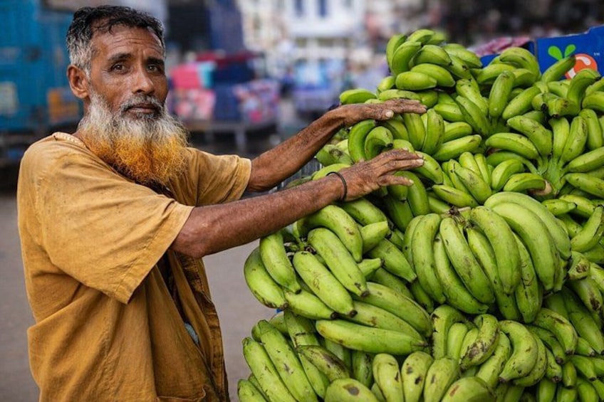 Une personne tenant une grande pile de bananes vertes. 3