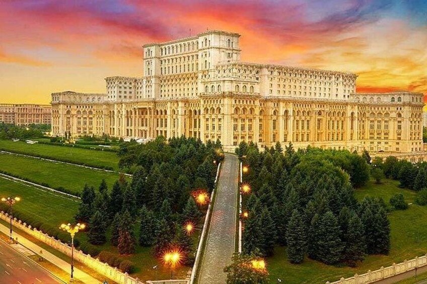 Un grand bâtiment imposant, doté d’une façade symétrique, entouré d’une pelouse parfaitement entretenue et d’un long chemin rectiligne menant à l’entrée. 4