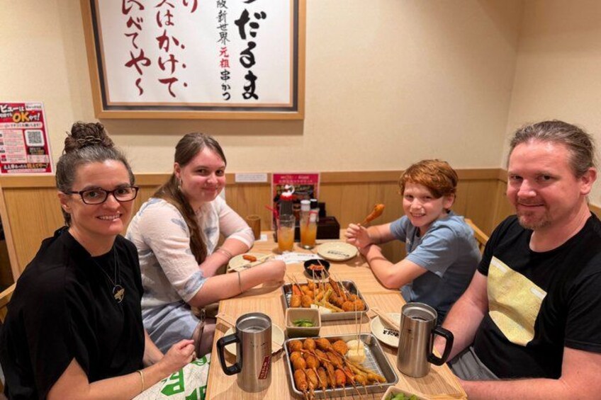 Un grupo de personas sentadas en una mesa con comida y bebidas. 3