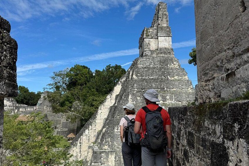 A large ancient pyramid structure with tourists observing it. 3