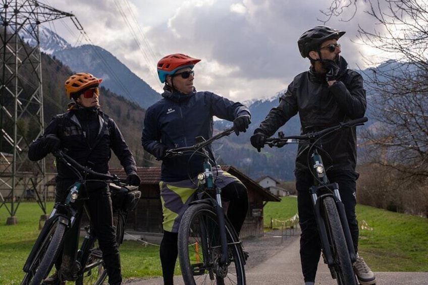 Tres personas en bicicleta en un entorno rural con montañas al fondo. 2