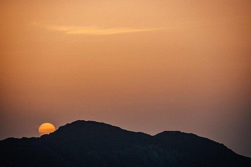 A sunset over a mountain range with a visible sun near the horizon. 2