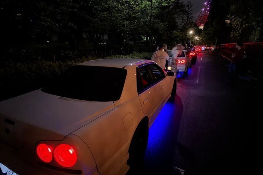 A car with blue underglow lights, parked on a road with other vehicles. 2