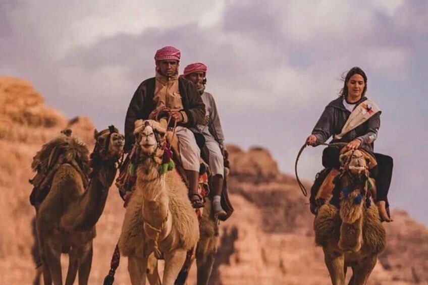 Un grupo de personas montando camellos en un paisaje desértico. 3