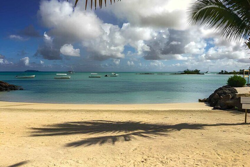 Ein Strand mit sandigem Ufer, ruhigem türkisblauem Wasser und mehreren Booten im Hintergrund. 4