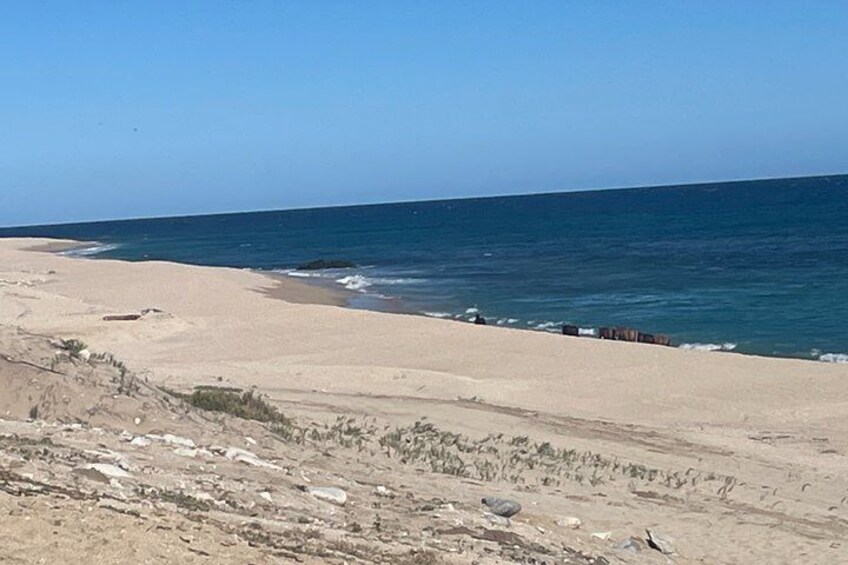 Una spiaggia con cielo sereno, mare calmo e terreno roccioso. 5