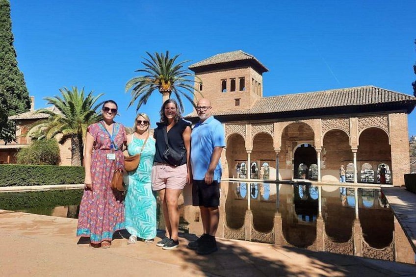 A group of people standing in front of a historic building with arches and a reflecting pool. 3