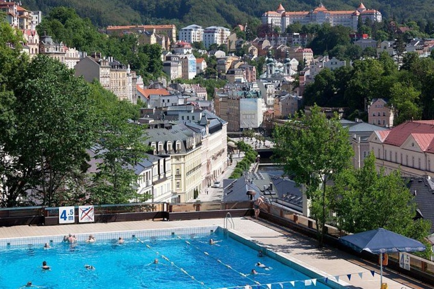 A swimming pool with people swimming, surrounded by buildings and trees. 2