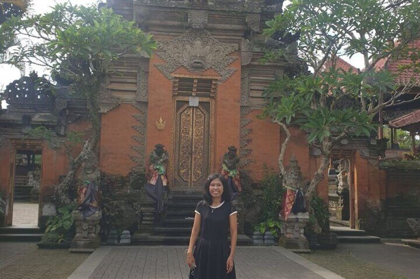 A woman standing in front of a traditional Balinese temple with ornate carvings and a large central door. 5