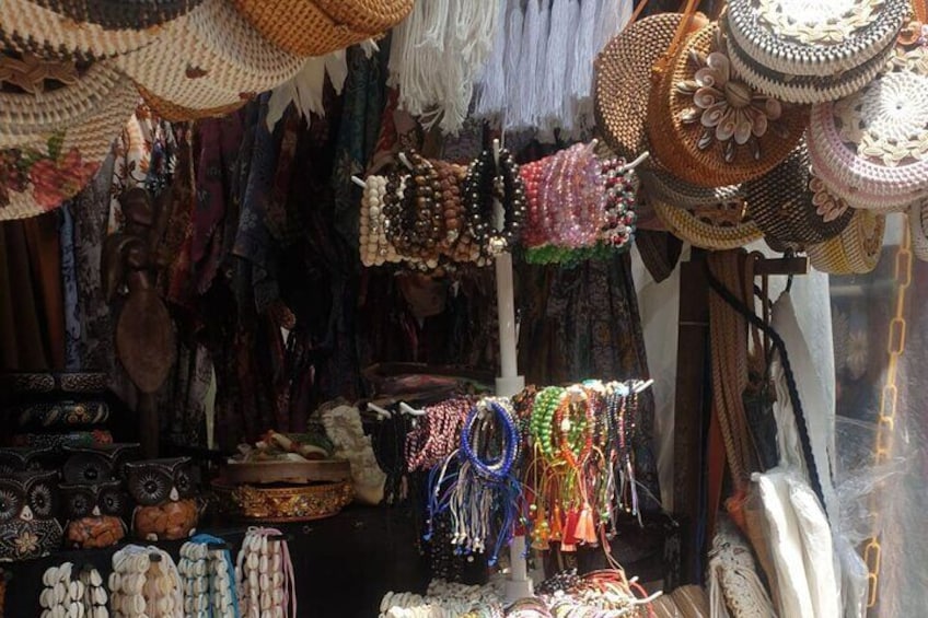 A market stall with various handmade items including woven baskets, colorful beaded necklaces, and traditional clothing. 4
