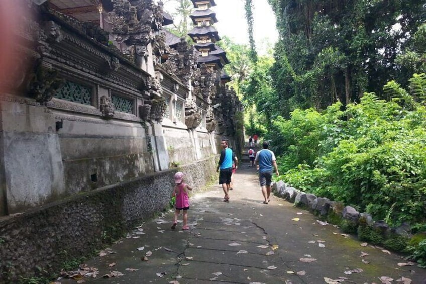 A pathway flanked by lush greenery and a stone structure with intricate carvings. 2