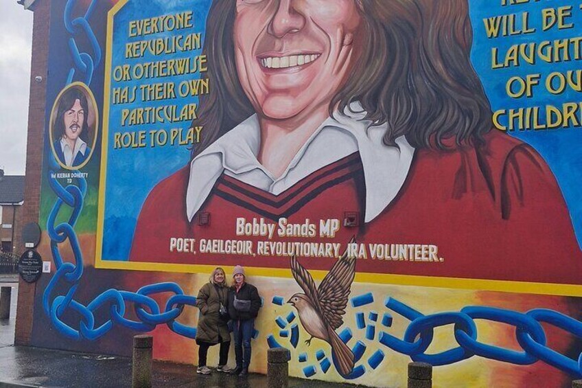 A mural with a person wearing a red shirt and a bird. There are chains and text on the mural. 3