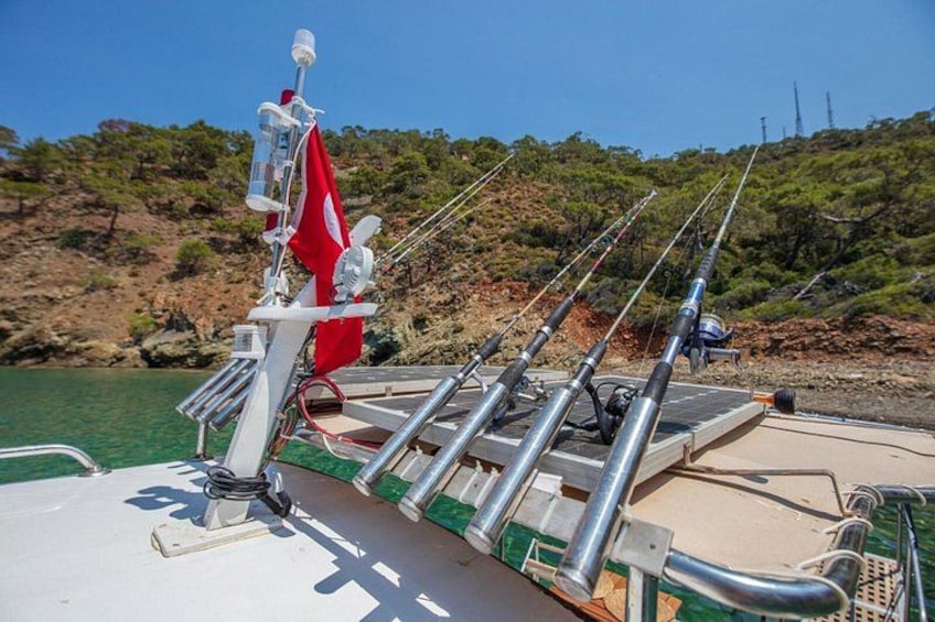 A boat docked with fishing rods and a red flag. 1