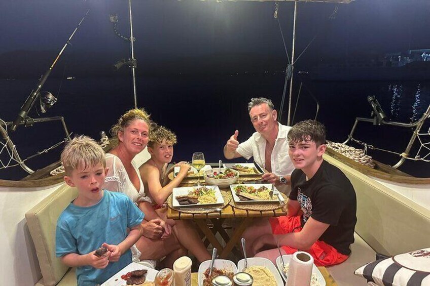 Un grupo de personas cenando en un barco, con una mesa dispuesta con comida y bebidas. 5