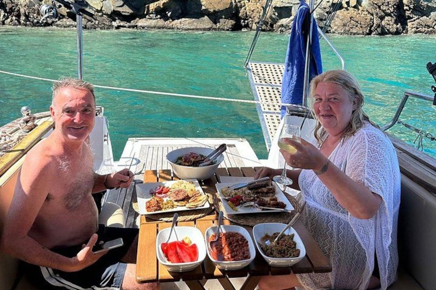 Deux personnes se trouvent sur un bateau, autour d’une table chargée de nourriture et de boissons. 4