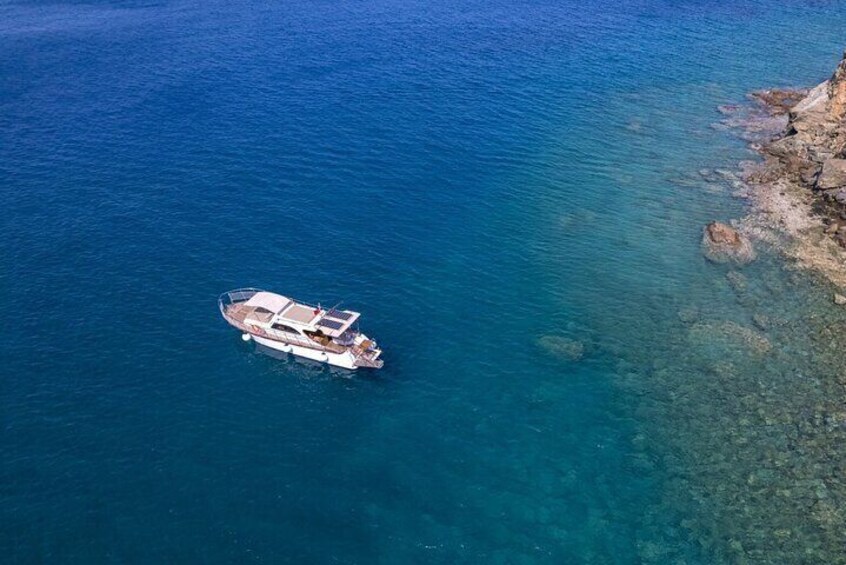 Un bote fondeado en aguas azul turquesa cerca de una costa rocosa. 2