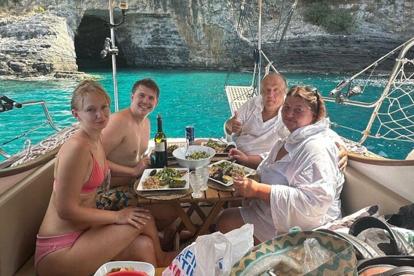 A group of people dining on a boat with a rocky coastline in the background. 5