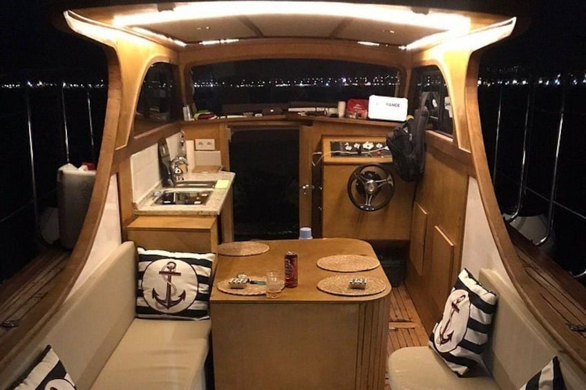 L'intérieur d'un bateau, avec un coin repas, une petite cuisine et un volant. 2